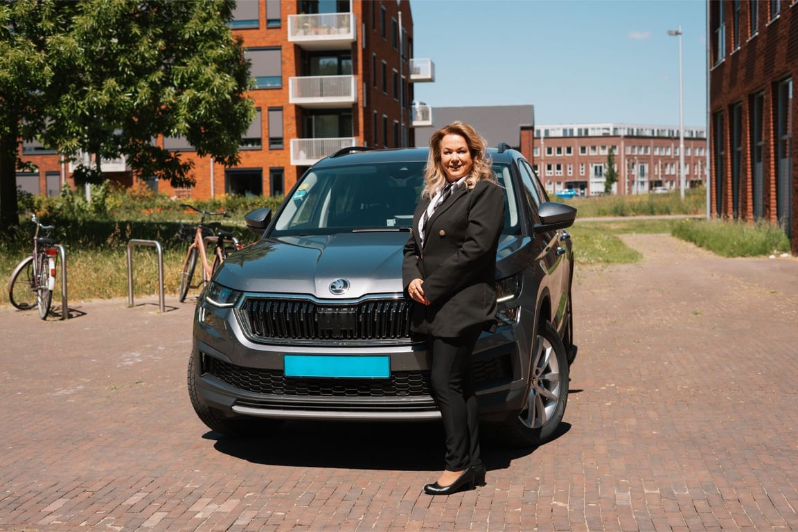 Een vervoerder van taxicentrale Rotterdam staand naast zijn taxi